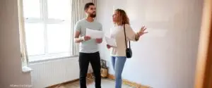 Mann und Frau unterhalten sich über Sanierung in einem renovierungsbedürftigen Zimmer.