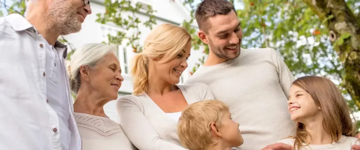 family, happiness, generation, home and people concept - happy family standing in front of house outdoors