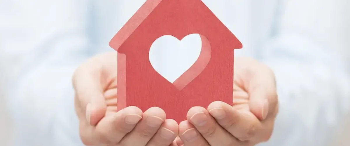 Small red house with heart in hands